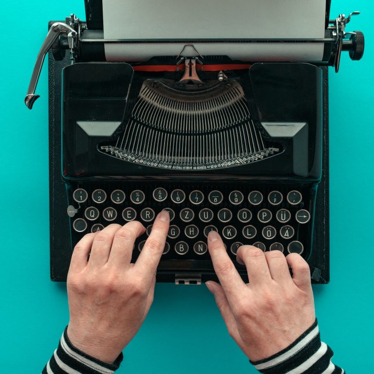 Woman typing vintage typewriter, top view
